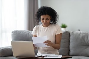 woman reviewing financial documents in front of a laptop