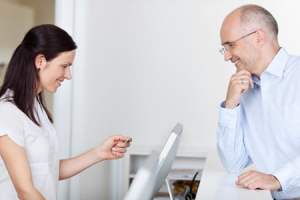 woman entering a man's insurance info into a computer